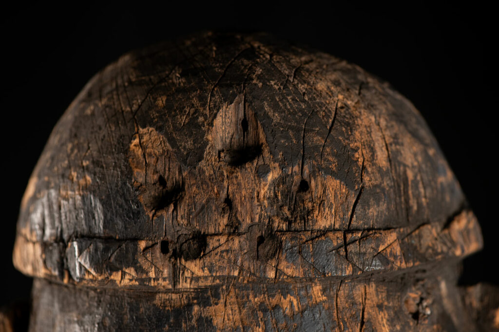 Tall ancient Paiwan tribe statue of an ancestor wearing a Paiwan dress , a hat - decoration of the hat are missing- and a bead collar.