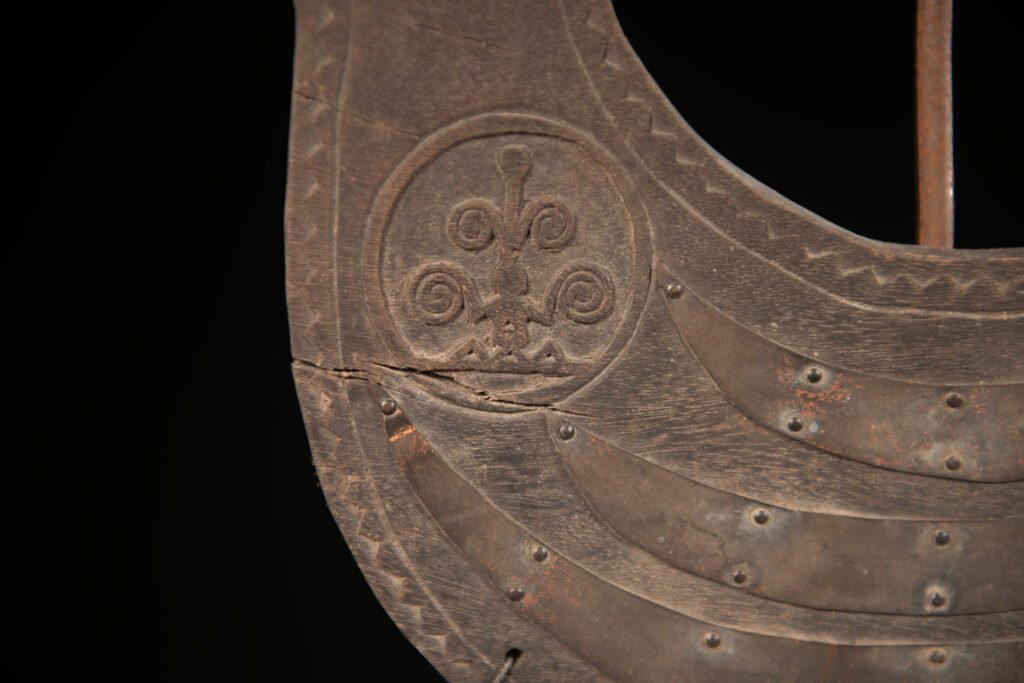 This half-moon-shaped chest ornament is made from wood chips of mangosteen, wuzhi (five-finger tree), or persimmon trees, and is traditionally worn by elderly men. Three arc-shaped copper pieces ( oxyded) of varying sizes are attached to the wooden base. The lower edge is adorned with various decorative elements considered beautiful.