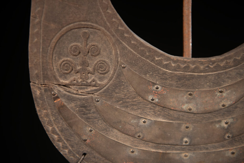 This half-moon-shaped chest ornament is made from wood chips of mangosteen, wuzhi (five-finger tree), or persimmon trees, and is traditionally worn by elderly men. Three arc-shaped copper pieces ( oxyded) of varying sizes are attached to the wooden base. The lower edge is adorned with various decorative elements considered beautiful.
