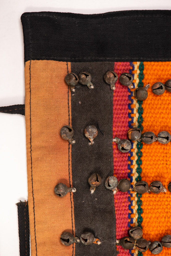 Antique Paiwan tribe women’s leggings made of red wool with black cotton panels and vertical stripes in pink, yellow, and orange. This traditional pair features eight rows of small copper bells and black cotton straps for tying around the calves. Such square leggings were worn over skirts to expose the lower legs and were decorated only by noblewomen. A rare example of formal Paiwan ceremonial wear from Taiwan's Indigenous heritage.