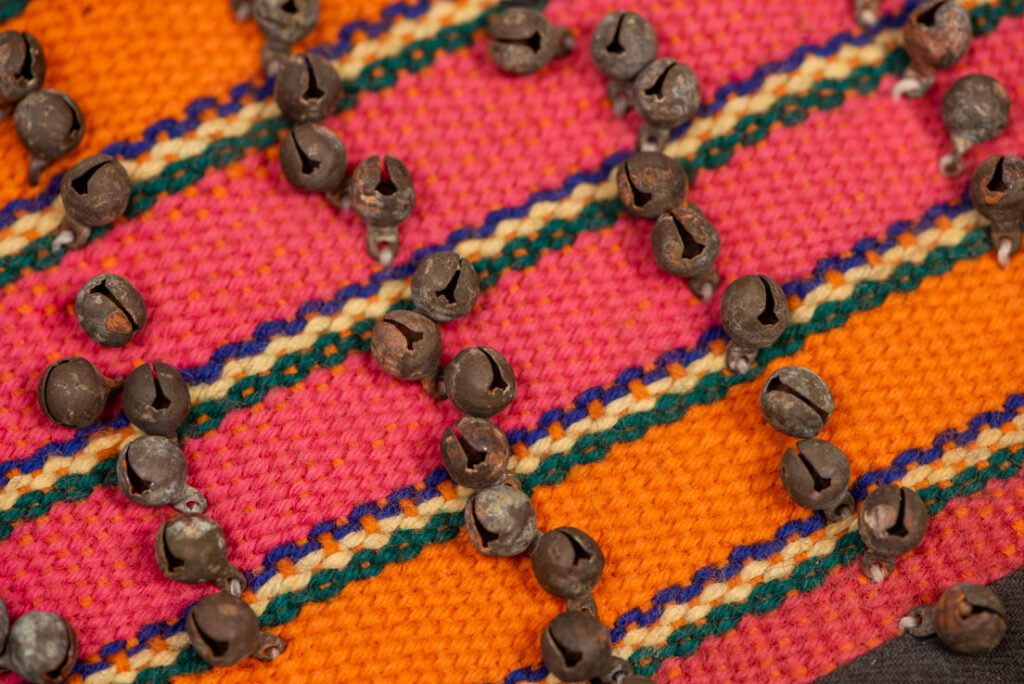 Antique Paiwan tribe women’s leggings made of red wool with black cotton panels and vertical stripes in pink, yellow, and orange. This traditional pair features eight rows of small copper bells and black cotton straps for tying around the calves. Such square leggings were worn over skirts to expose the lower legs and were decorated only by noblewomen. A rare example of formal Paiwan ceremonial wear from Taiwan's Indigenous heritage.