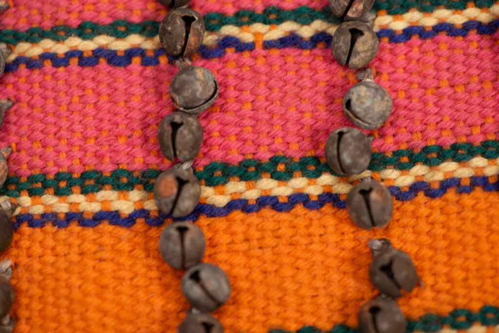 Antique Paiwan tribe women’s leggings made of red wool with black cotton panels and vertical stripes in pink, yellow, and orange. This traditional pair features eight rows of small copper bells and black cotton straps for tying around the calves. Such square leggings were worn over skirts to expose the lower legs and were decorated only by noblewomen. A rare example of formal Paiwan ceremonial wear from Taiwan's Indigenous heritage.