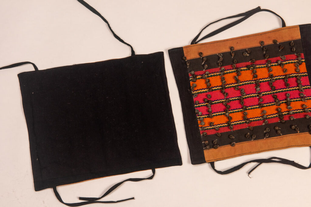 Antique Paiwan tribe women’s leggings made of red wool with black cotton panels and vertical stripes in pink, yellow, and orange. This traditional pair features eight rows of small copper bells and black cotton straps for tying around the calves. Such square leggings were worn over skirts to expose the lower legs and were decorated only by noblewomen. A rare example of formal Paiwan ceremonial wear from Taiwan's Indigenous heritage.