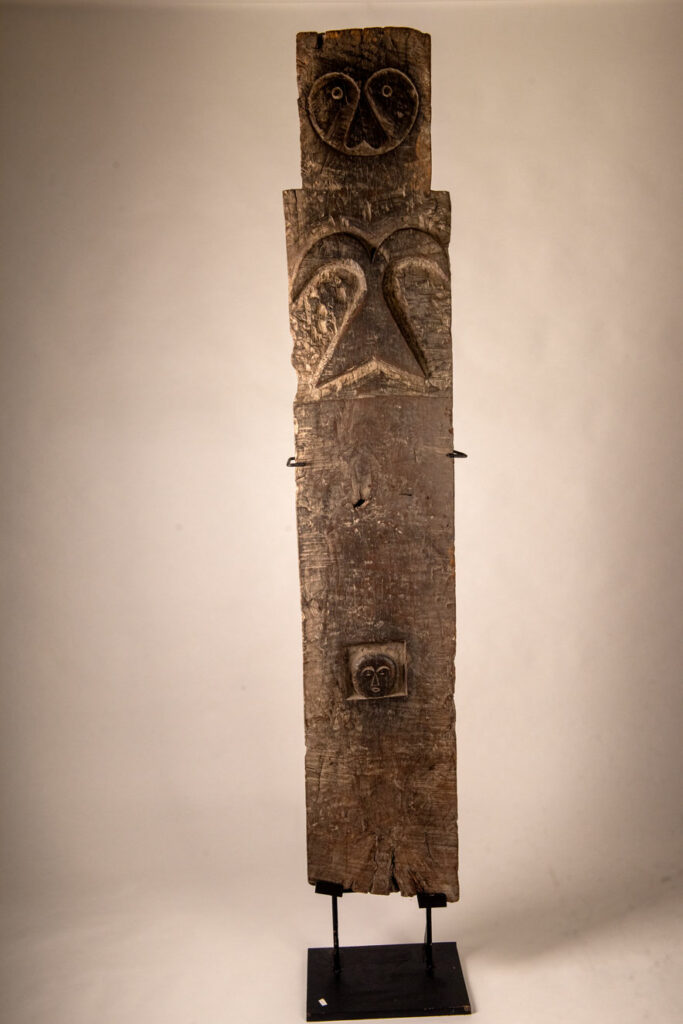 Rare and massive early 19th-century panel from the East Coast Paiwan tribe, carved in the Taimali style. It features a prominent central nose, a stylized face at the top, and another face carved at the bottom — a characteristic design of the Southeastern Paiwan tradition.