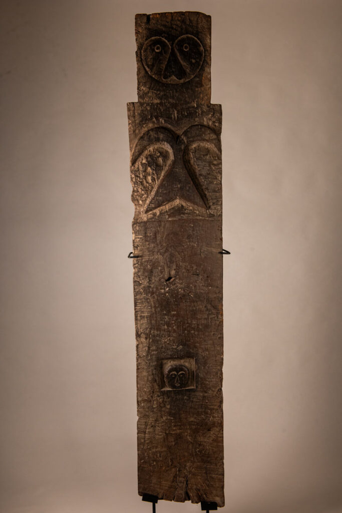 Rare and massive early 19th-century panel from the East Coast Paiwan tribe, carved in the Taimali style. It features a prominent central nose, a stylized face at the top, and another face carved at the bottom — a characteristic design of the Southeastern Paiwan tradition.