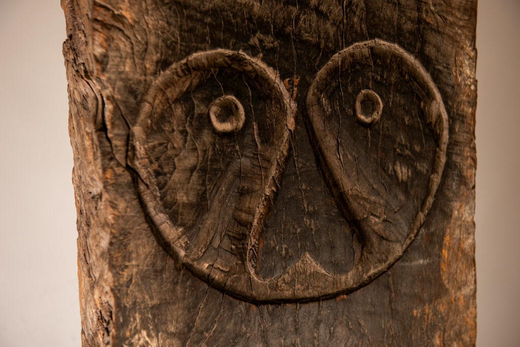 Rare and massive early 19th-century panel from the East Coast Paiwan tribe, carved in the Taimali style. It features a prominent central nose, a stylized face at the top, and another face carved at the bottom — a characteristic design of the Southeastern Paiwan tradition.