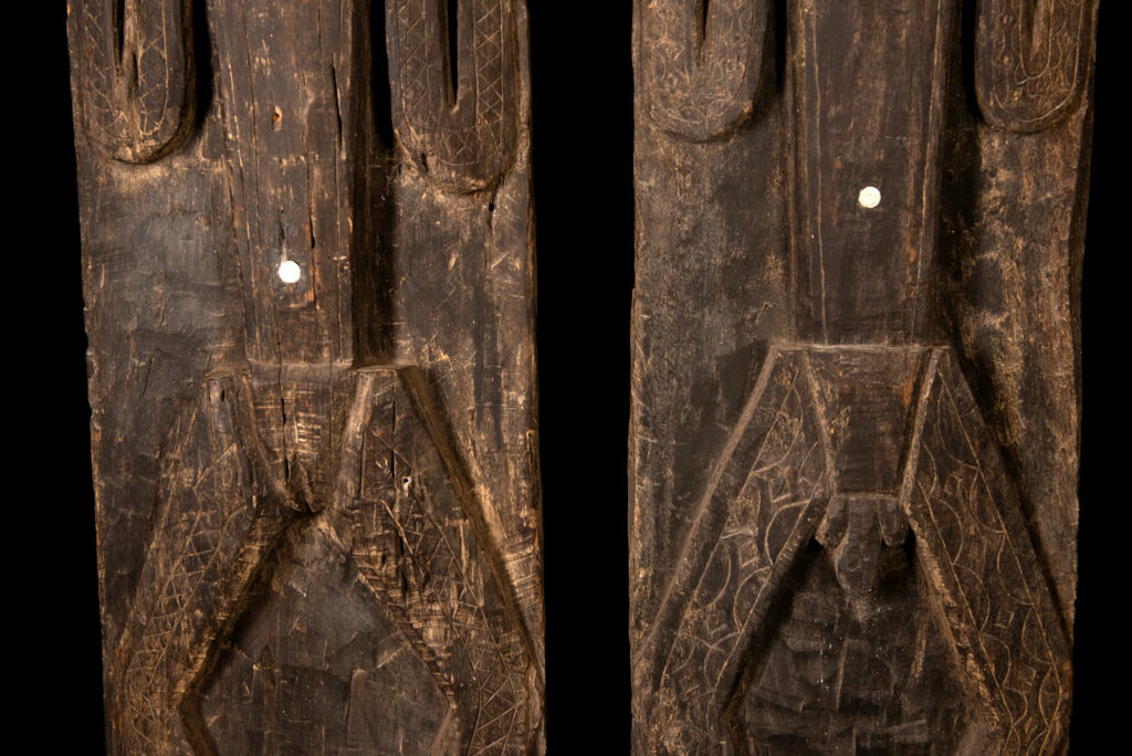Pair of Paiwan Tribe Ancestor Panels, likely from Laiyi, carved with two figures—a male and a female. Their eyes, mouth, nipples, and navel are inlaid with porcelain. Their arms and legs are decorated with tribal motifs suggesting tattoos. Both figures wear hats, and the snakes carved above their heads indicate that they were important members of the nobility.