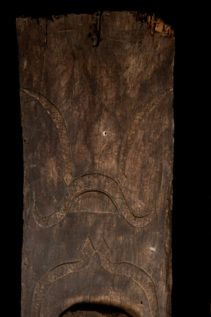 Pair of Paiwan Tribe Ancestor Panels, likely from Laiyi, carved with two figures—a male and a female. Their eyes, mouth, nipples, and navel are inlaid with porcelain. Their arms and legs are decorated with tribal motifs suggesting tattoos. Both figures wear hats, and the snakes carved above their heads indicate that they were important members of the nobility.