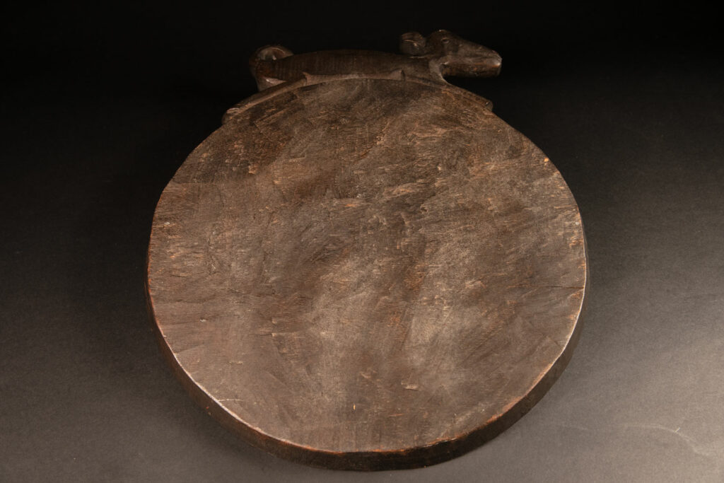 Ceremonial Tray from the Paiwan Tribe Carved with snakes, human faces, and game animals such as deer and wild boar, topped with a sculpture of a deer .
