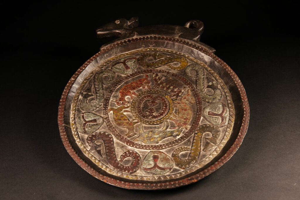 Ceremonial Tray from the Paiwan Tribe Carved with snakes, human faces, and game animals such as deer and wild boar, topped with a sculpture of a deer .