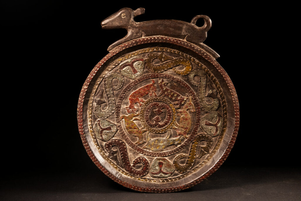 Ceremonial Tray from the Paiwan Tribe Carved with snakes, human faces, and game animals such as deer and wild boar, topped with a sculpture of a deer .