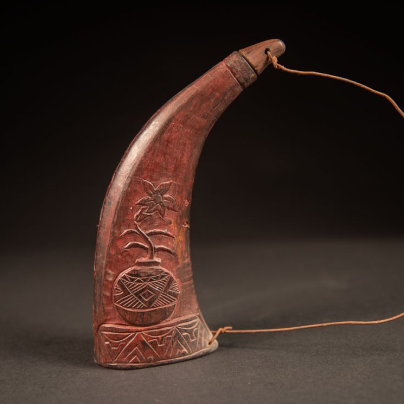 Powder flask from the Rukai tribe, made from a horn sealed at the base with a wooden plug. the body is carved on 2 sides and tint in red .