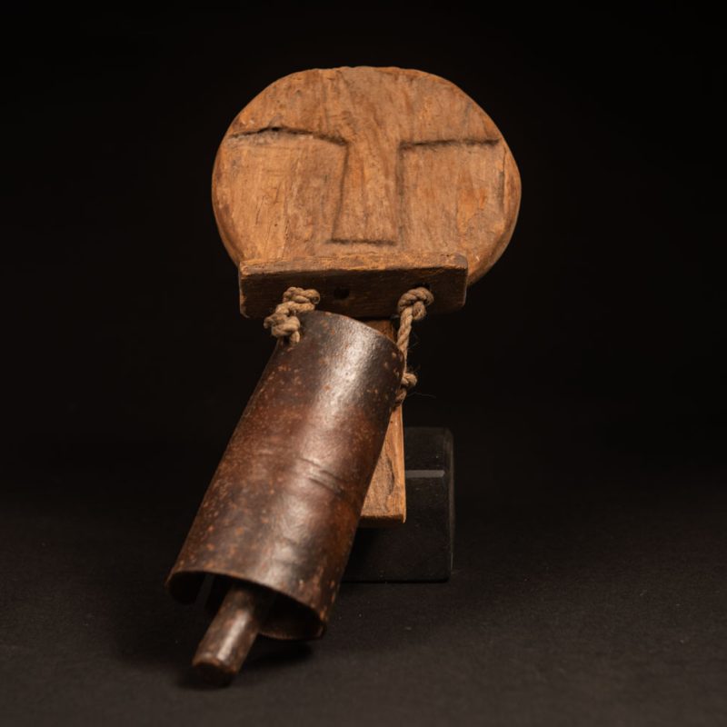 Rukai tribe alarm bell showing a wooden handle shaped with a human face linked with a cylindrical bell .