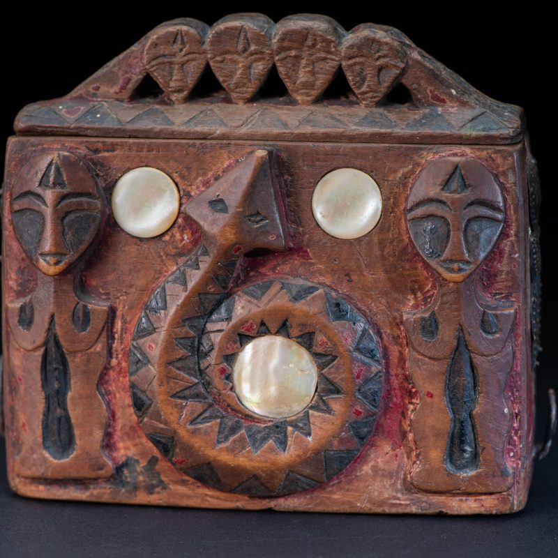 Paiwan tribe Shaman box with a sliding lid topped with carved faces, painted with red pigments, featuring full-length figures and the sacred snake, and decorated with mother-of-pearl.
