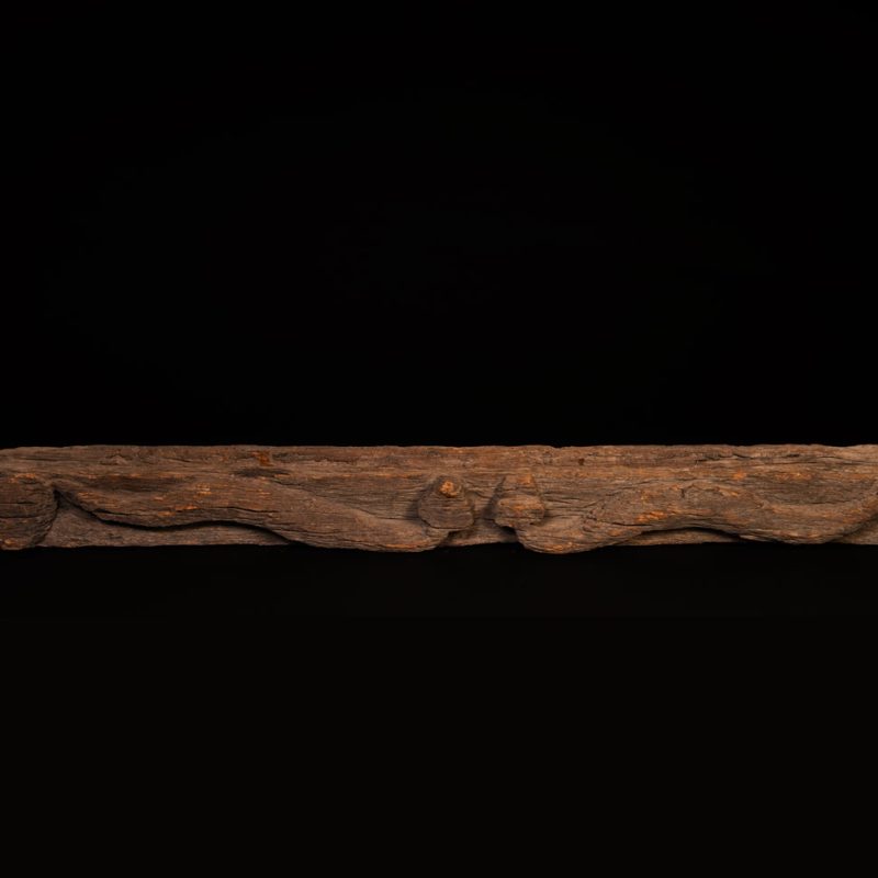 19th-century door lintel from the Paiwan tribe, carved with a pair of snakes facing each other and two human faces on either side. This Paiwan panel is heavily eroded and was probably placed above the entrance, exposed to the elements.