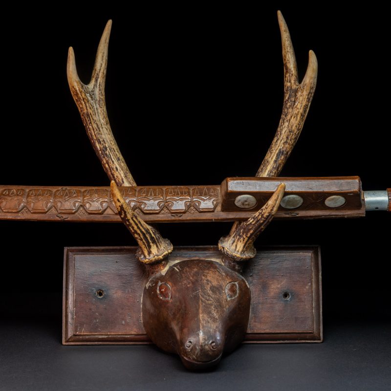 Very fine old sword from the Paiwan tribe, with a scabbard carved with multiple human faces. One side is inlaid with three faience circles.