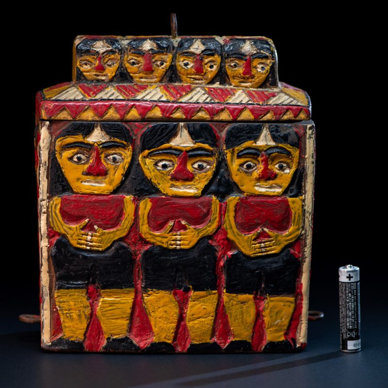 Paiwan tribe shaman box features a sliding lid, carved with human heads and painted in red, yellow, white, and black. Standing figure is carved on the other sides.