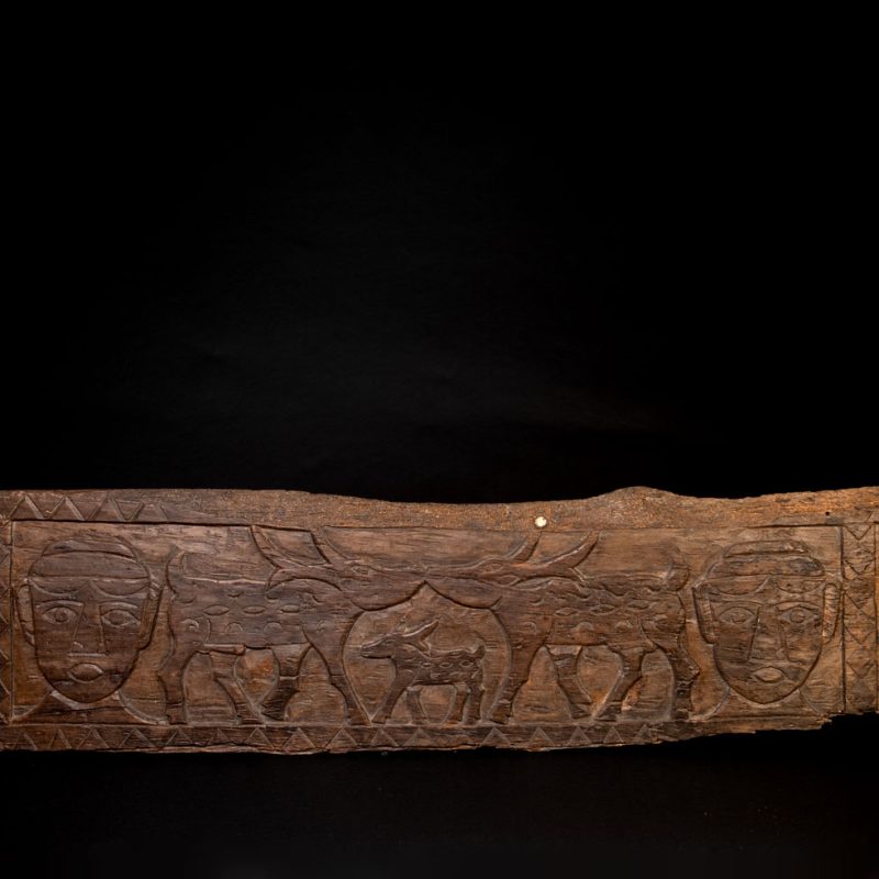 Ancient 19 century Paiwan tribe house eave carved with four human faces and three deers, two big and one small in the middle.