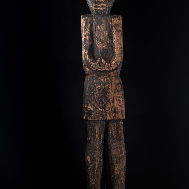 Tall ancient Paiwan tribe statue of an ancestor wearing a Paiwan dress , a hat - decoration of the hat are missing- and a bead collar.
